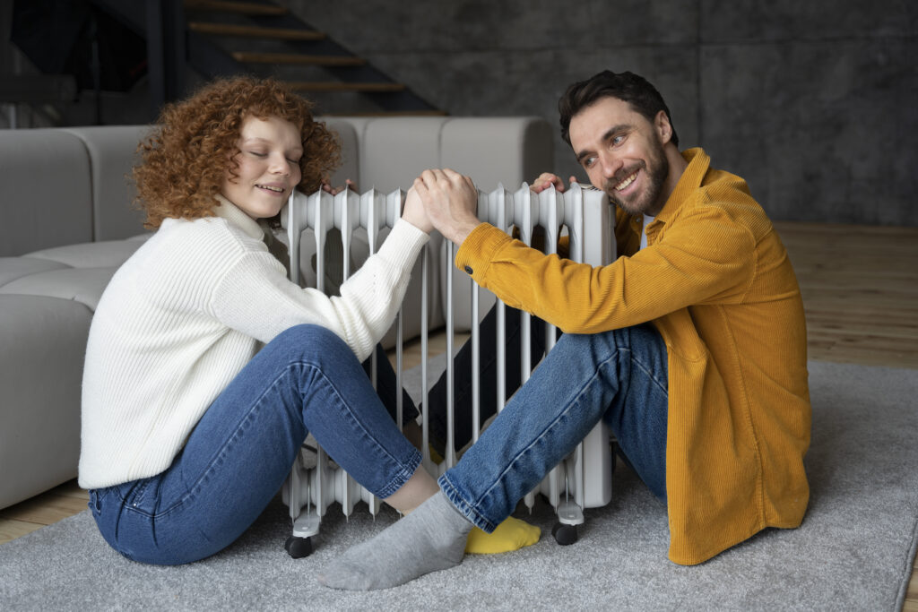 A fun smiling couple warming up around a heater